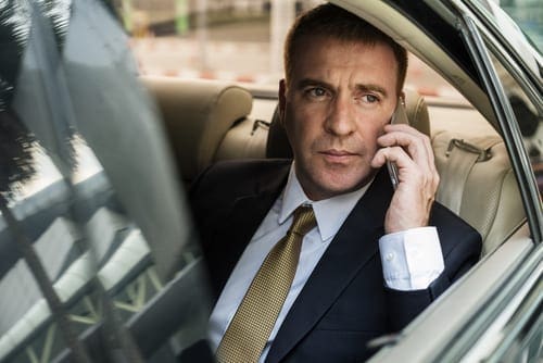 crown chauffeur cars melbourne fleet corporate executive traveling at rear seat and talking on a mobile phone